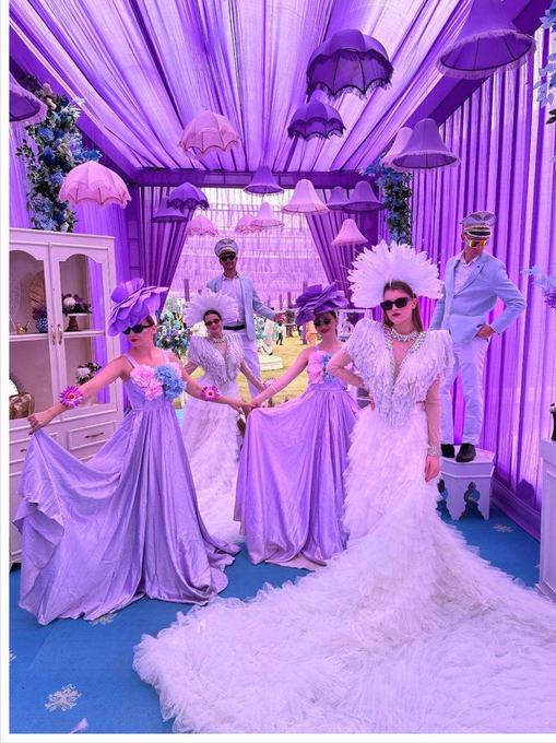 Performers in purple welcoming guests
