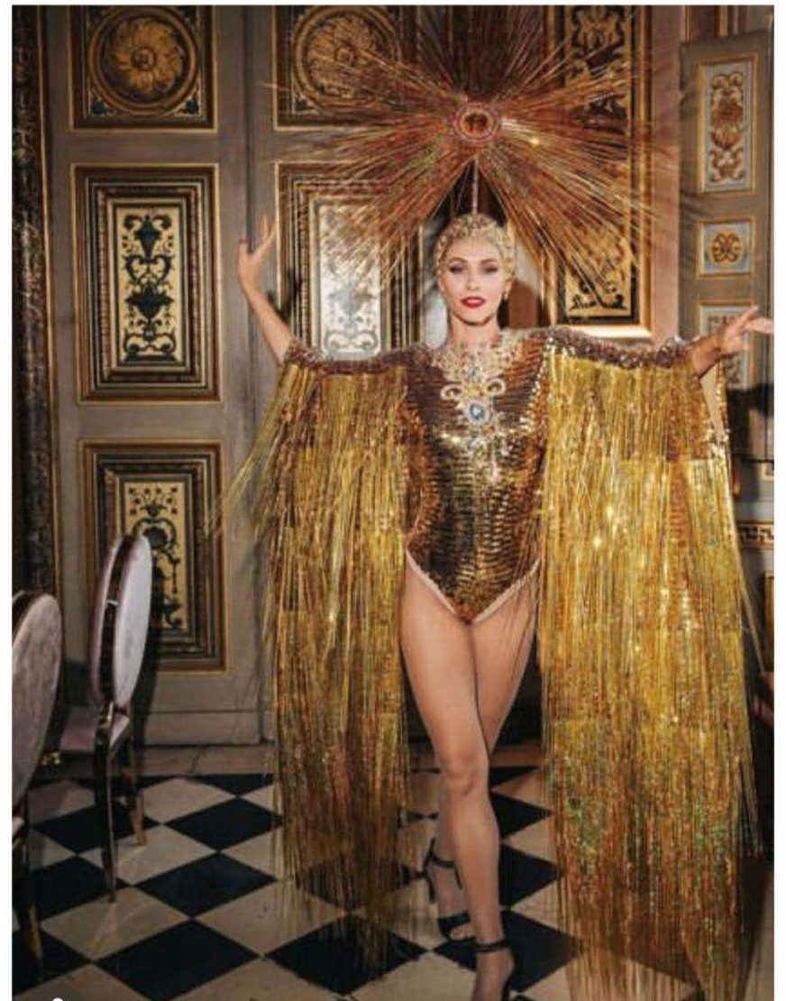 Performer in a gold fringed costume beneath a sunburst headdress